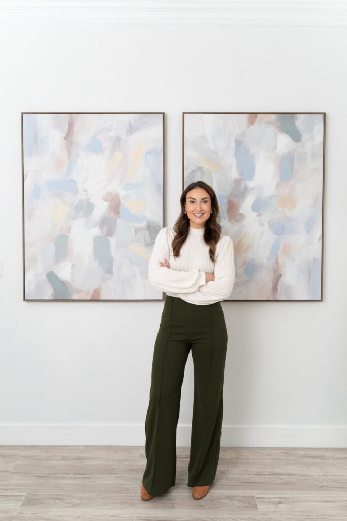 Woman standing in front of 2 pieces of artwork looking confident